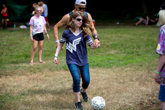 A visually impaired girl kicking a soccer ball.