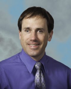 Shawn Kelly. He is wearing a purple shirt with a grey and purple tie.