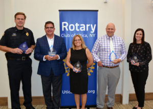 A group of people standing with awards in front of a Rotary banner